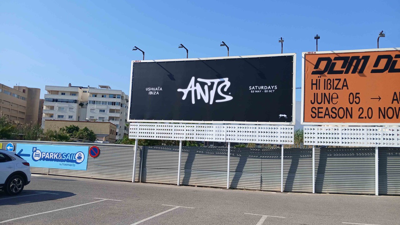 Valla de la fiesta ANTS en Ushuaïa Ibiza junto a otras vallas de club en un aparcamiento de Ibiza